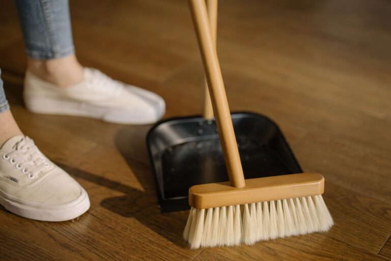 Professional cleaner sweeping a hardwood floor in a Maine business entryway in autumn, preparing for winter foot traffic