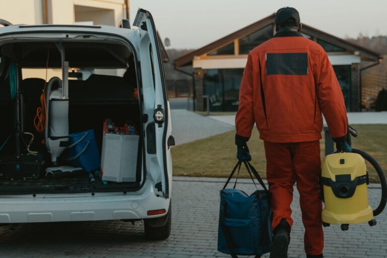 Professional cleaner in uniform walking toward a commercial building with cleaning equipment, preparing for a fall deep cleaning service in Maine